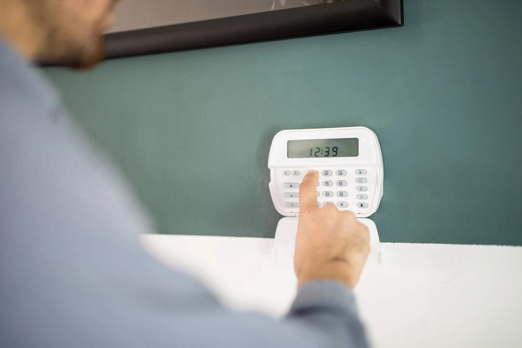 Close-up of a man arming his home security system using a keypad